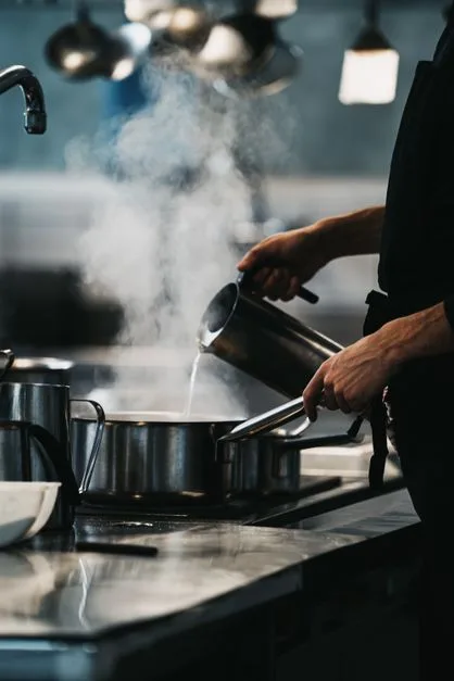 Steam rising in commercial kitchen showing why exhaust fan cleaning matters